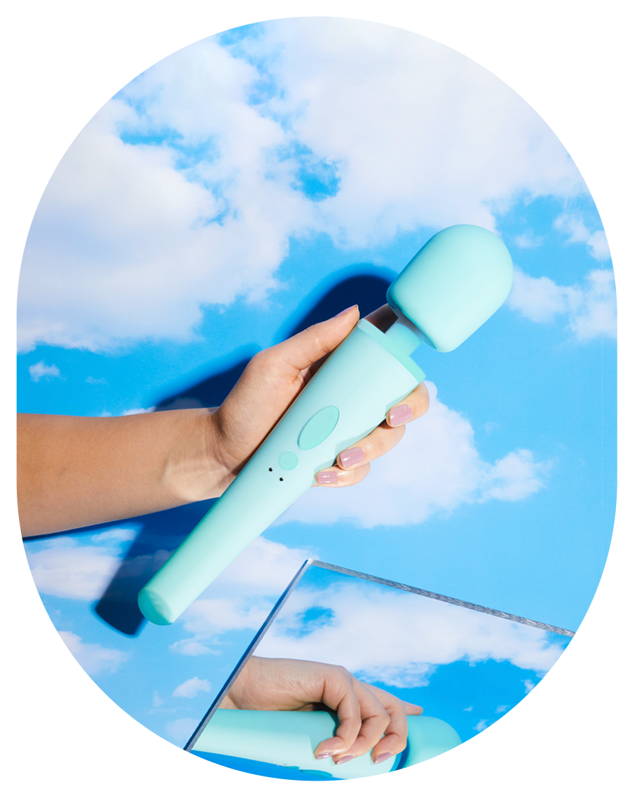 Hand holding the aqua Ollie wand vibrator against a cloudy blue sky
